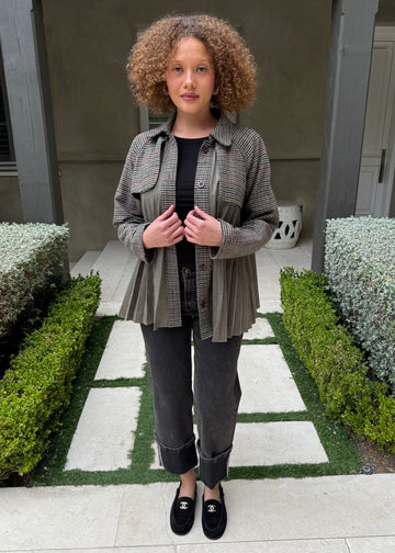 Woman standing in a garden with green bushes and a building in the background