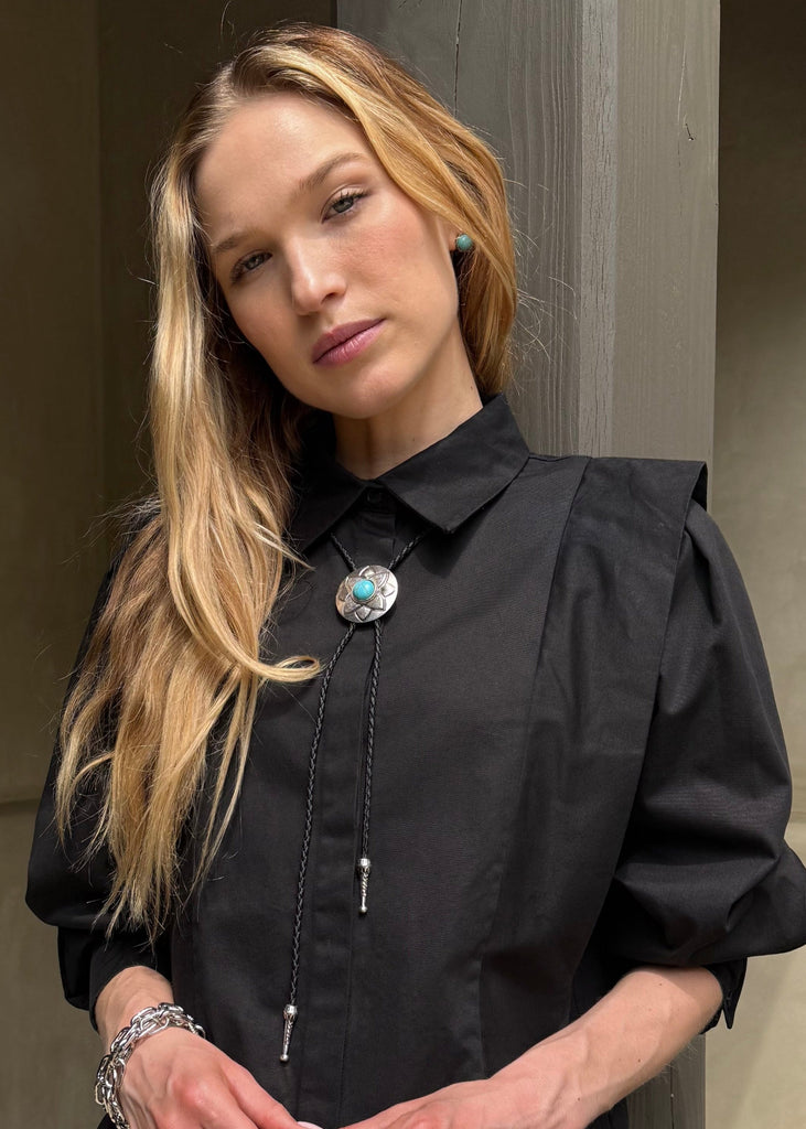 Woman in a black coat standing on steps outside a building