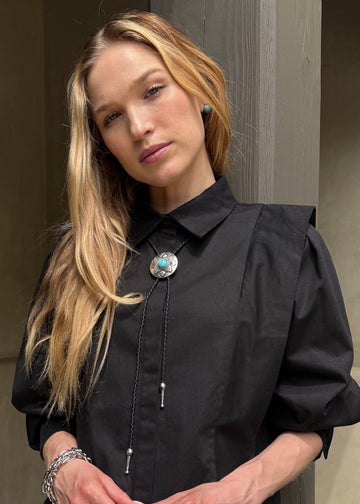 Woman in a black coat standing on steps outside a building