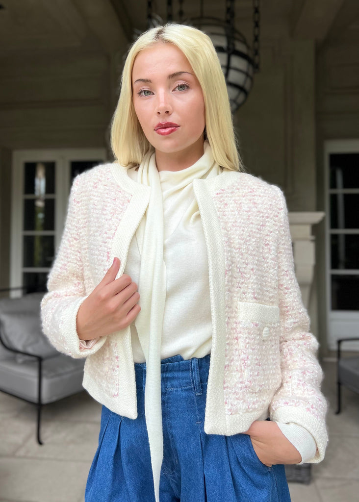 Woman wearing a white textured jacket and blue pants in an outdoor setting