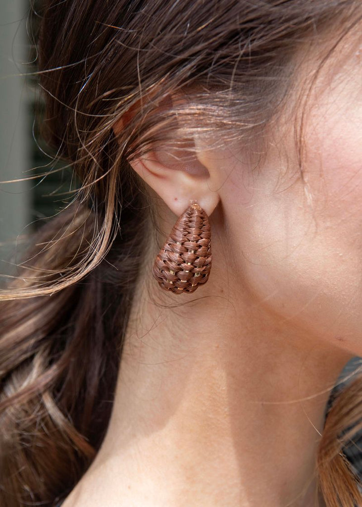 Close-up of a person wearing a textured copper earring.