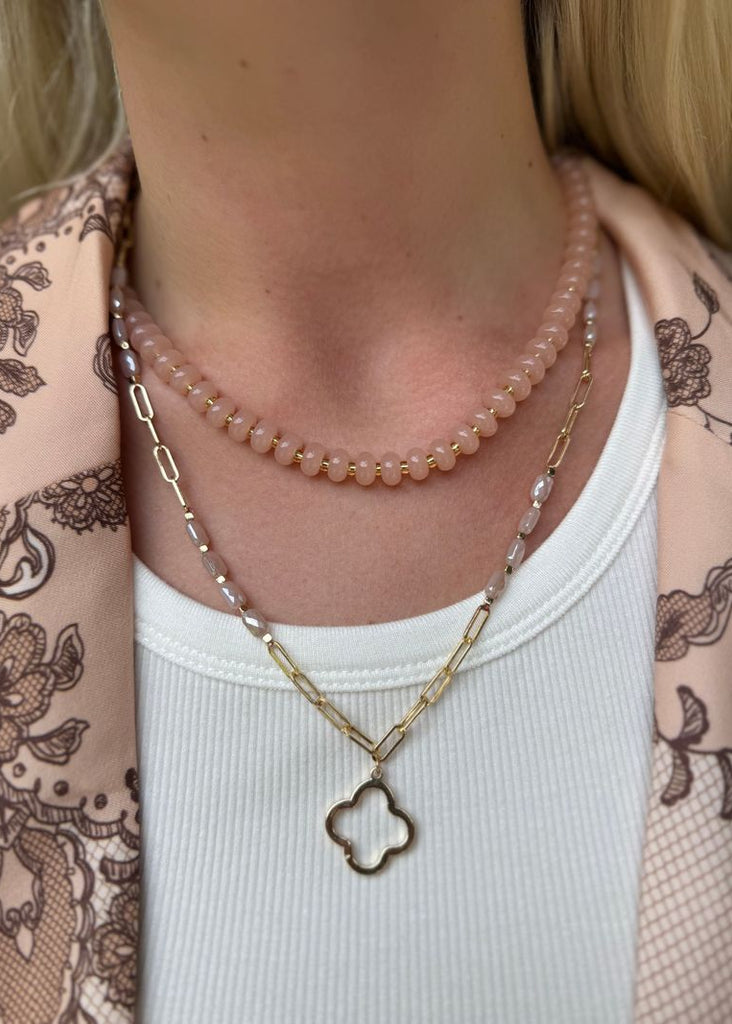 Necklace with a clover-shaped pendant worn by a person