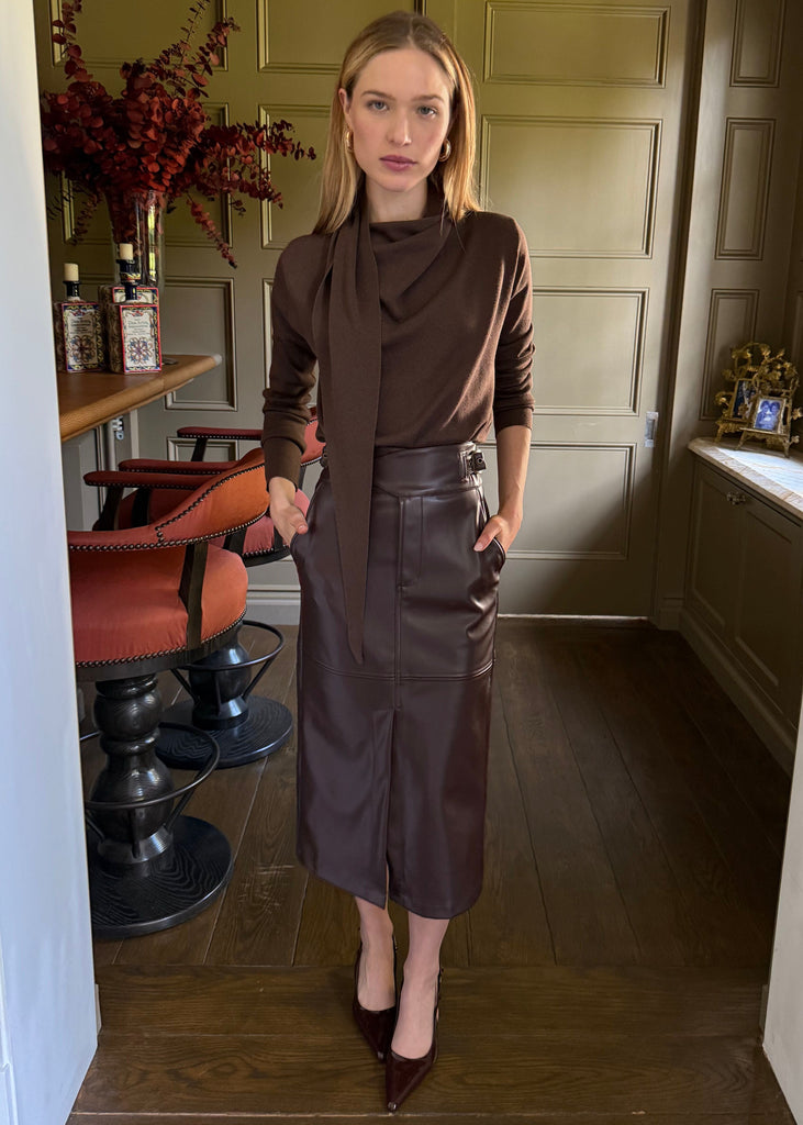 Woman in a brown outfit standing in a room with decor elements.