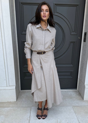 Woman in a beige outfit standing in front of a dark gray door.
