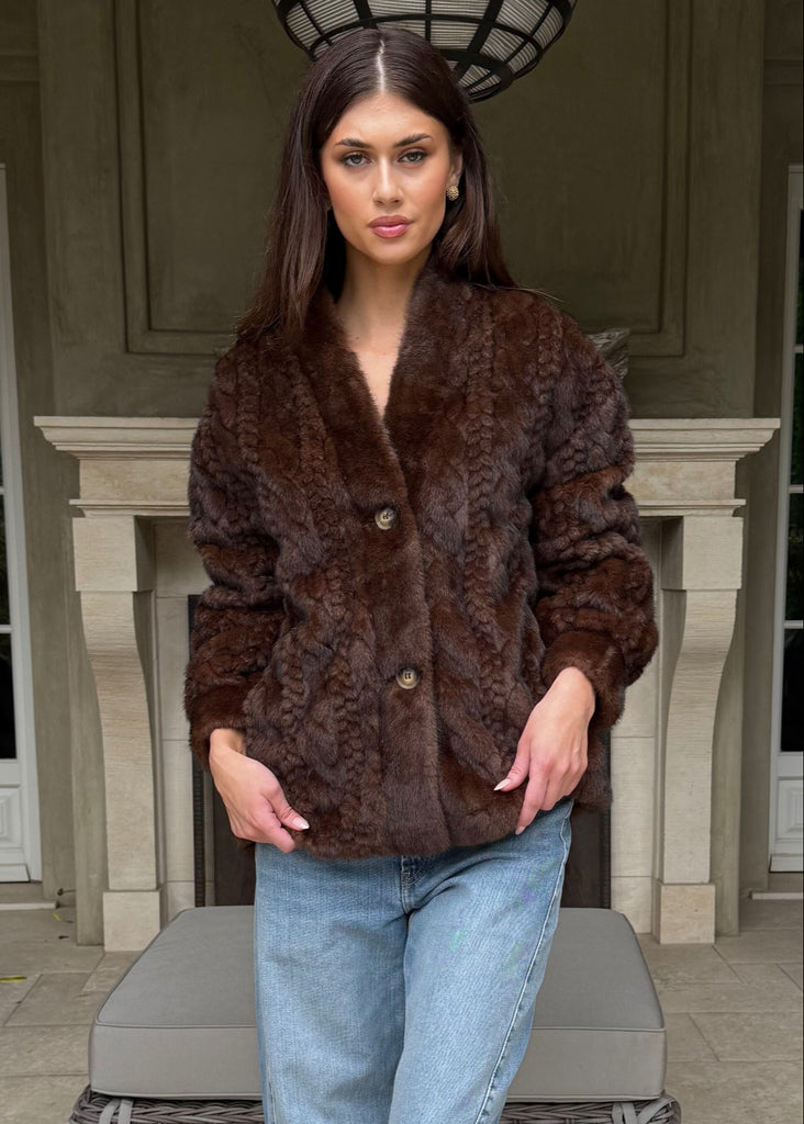 Woman wearing a brown fur coat and blue jeans on a patio