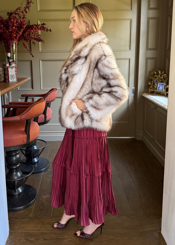 Woman wearing a fur coat and red skirt in a room with a dining table and chairs.