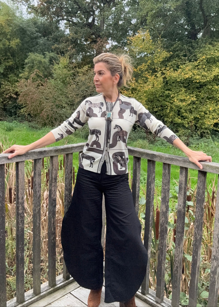 Woman standing on a wooden deck with greenery in the background