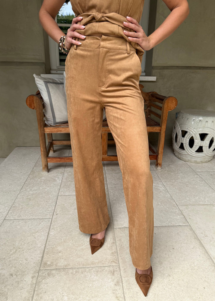 Person wearing a brown jumpsuit standing on a tiled floor.