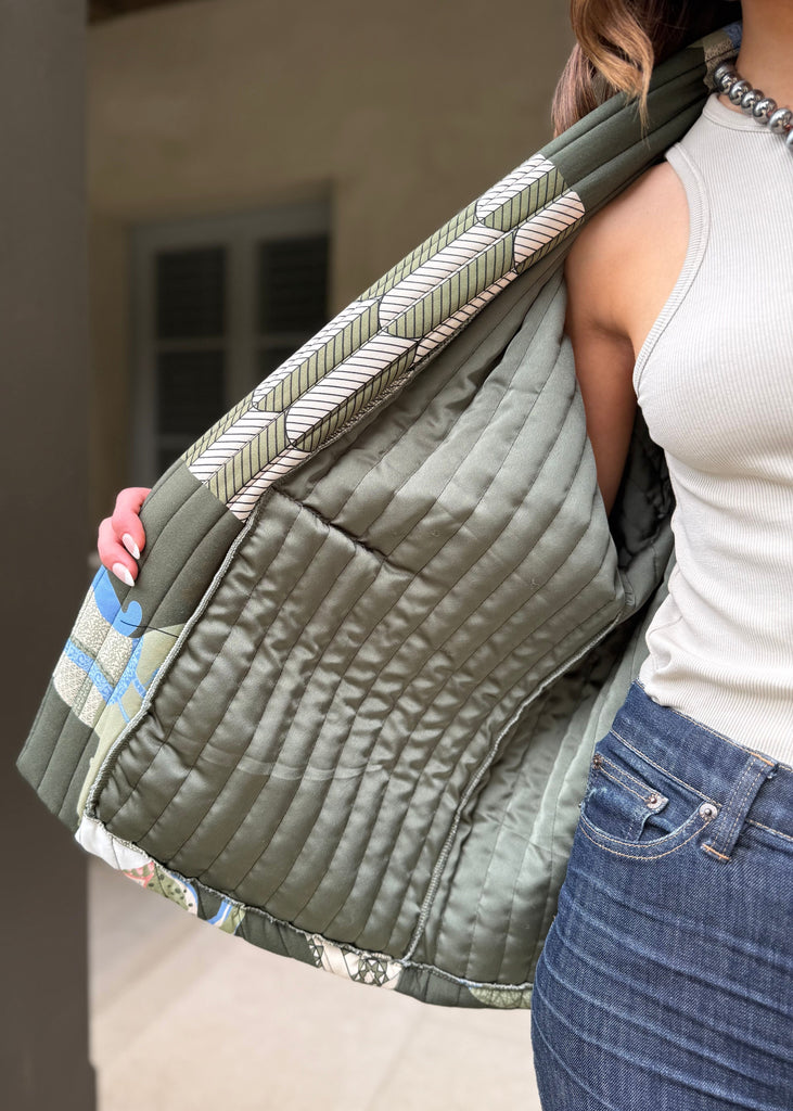 Person wearing a green quilted jacket with a neutral background
