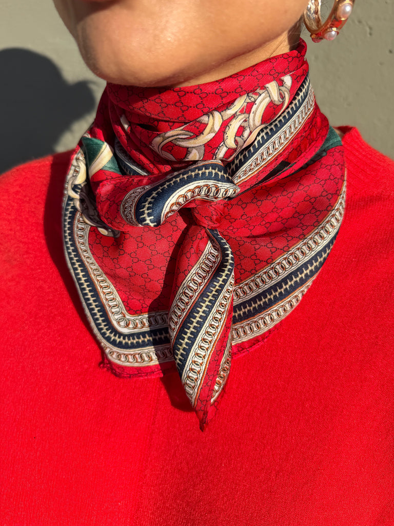 Person wearing a red patterned scarf on a plain background