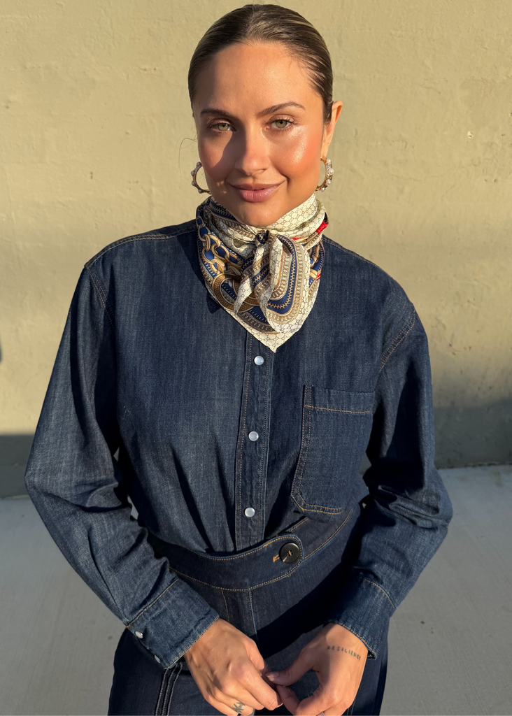 Person wearing a denim shirt and patterned scarf against a plain background