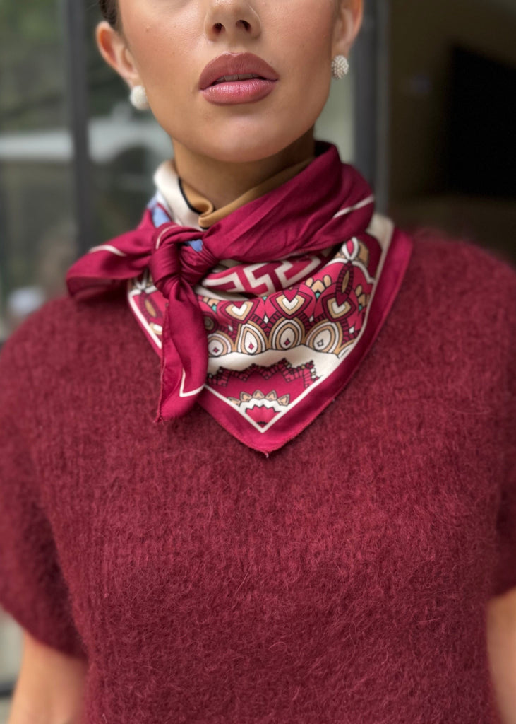 Woman wearing a red sweater and patterned scarf outdoors