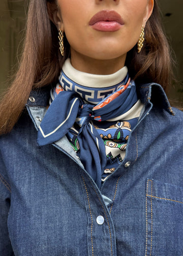 Woman wearing a blue denim jacket with a patterned scarf around her neck.