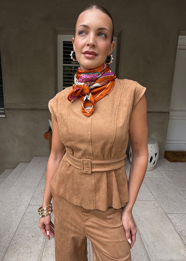 Woman wearing a brown outfit with a colorful scarf in an outdoor setting