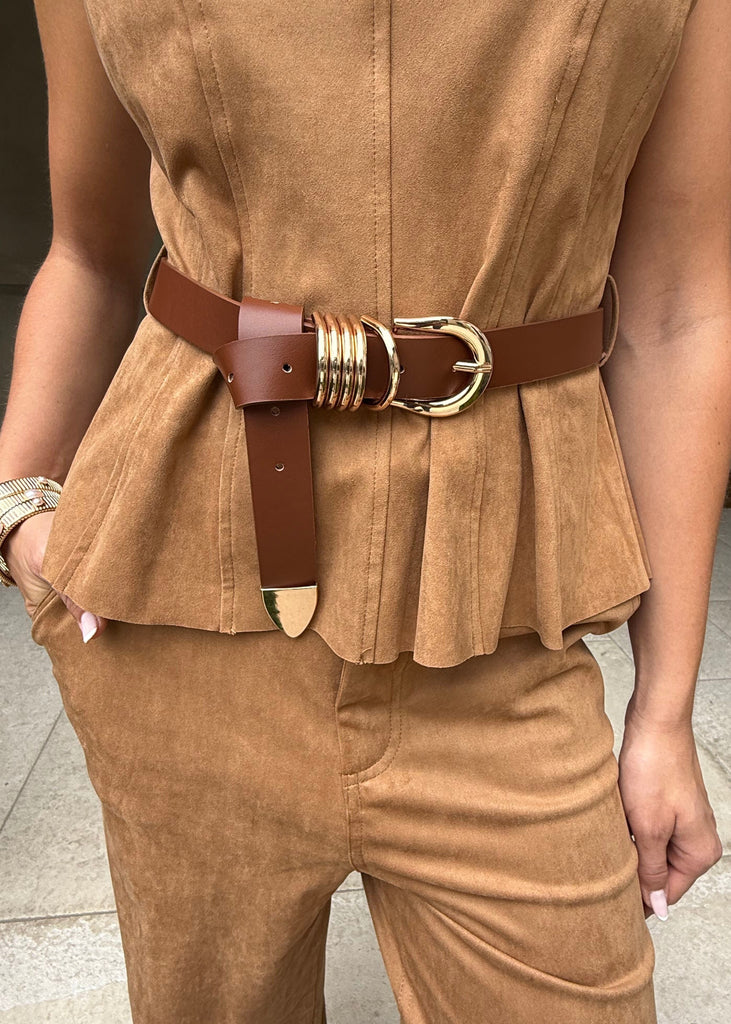 Person wearing a brown sleeveless top and pants with a decorative belt.