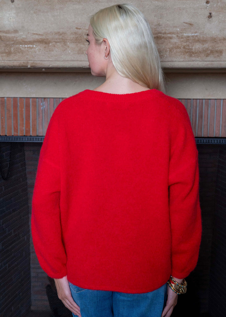 Person wearing a red sweater standing in front of a wooden wall.