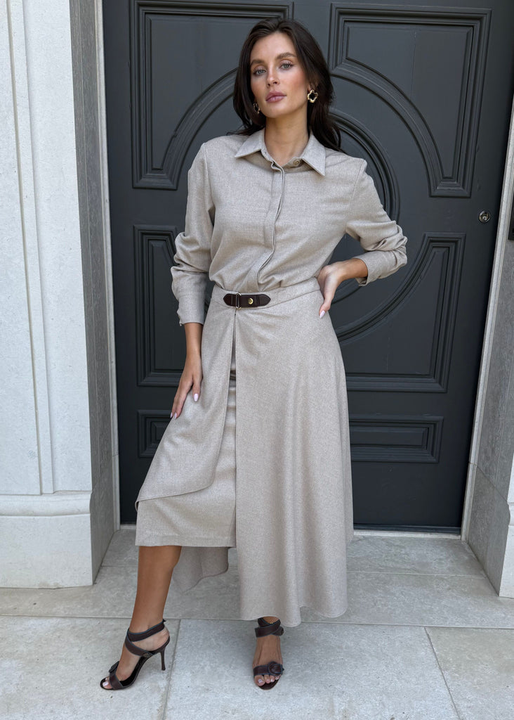 Woman in a beige dress standing in front of a dark door.