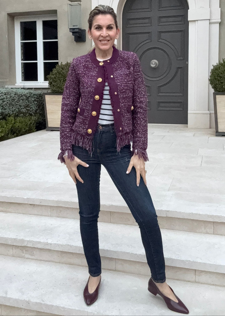 Woman in a purple jacket standing on steps in front of a building with a gray door.
