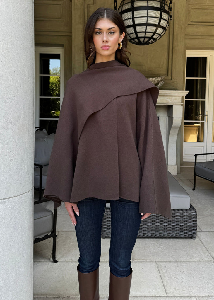 Woman wearing a brown cape in an elegant outdoor setting