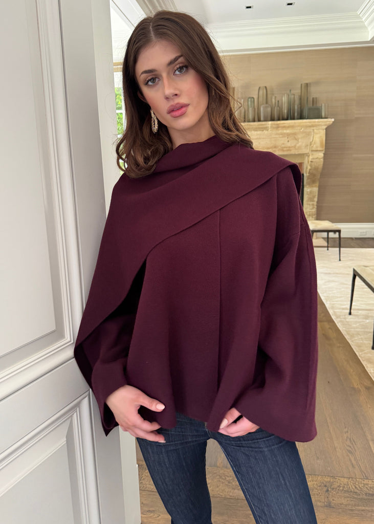 Woman wearing a burgundy poncho in an indoor setting