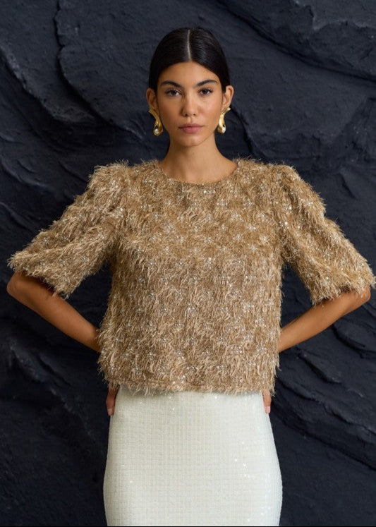 Woman wearing a textured beige top against a dark background