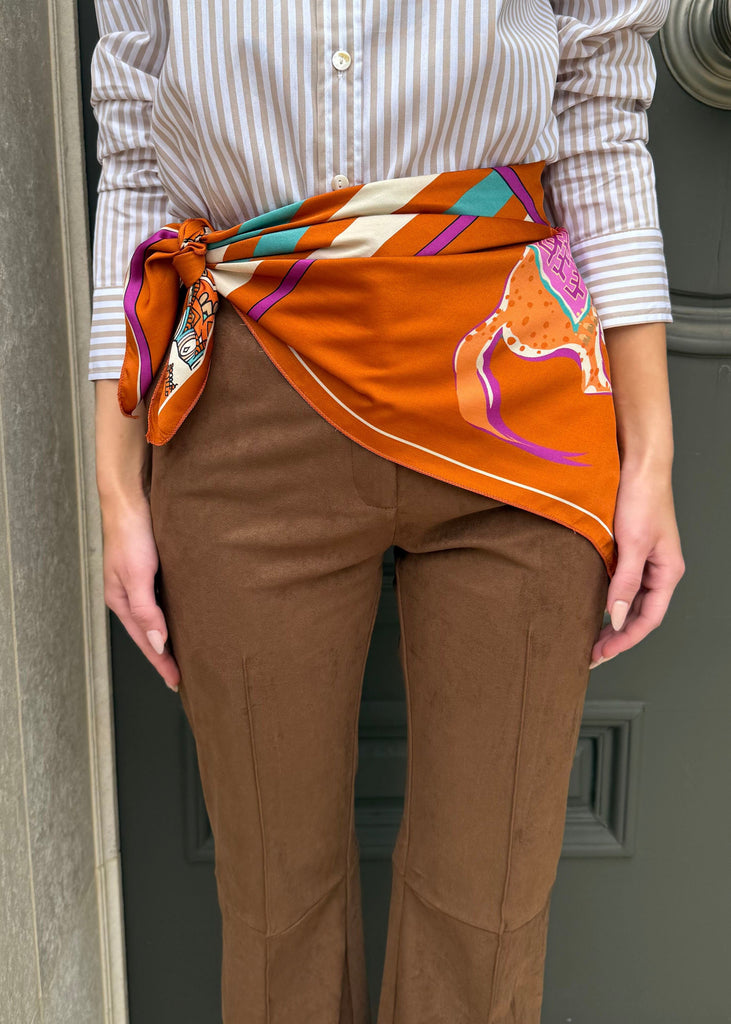 Person wearing a colorful scarf tied around their waist in front of a door.