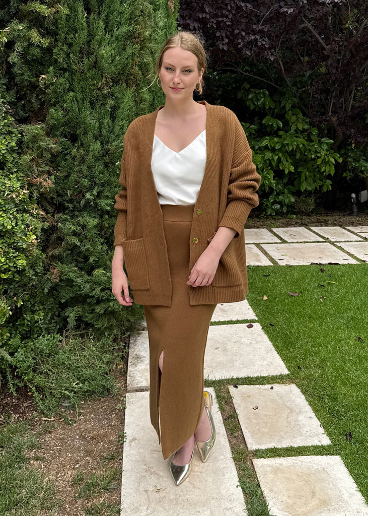 Woman in a brown suit standing on a garden path with greenery around