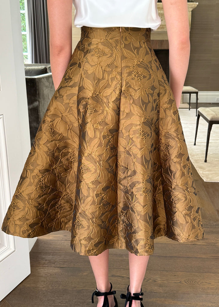 Person wearing a gold floral skirt in an indoor setting