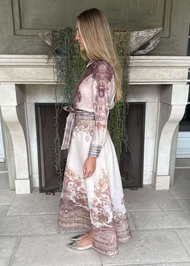 Woman in a floral dress standing in front of a fireplace
