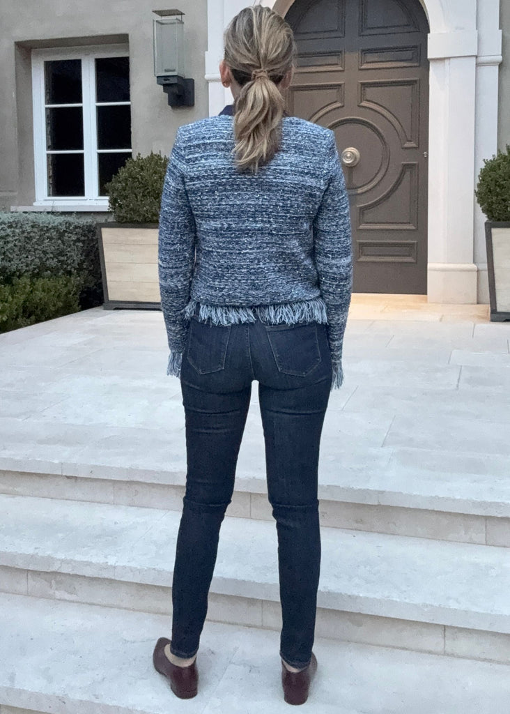 Person standing in front of a large house with a decorative door.