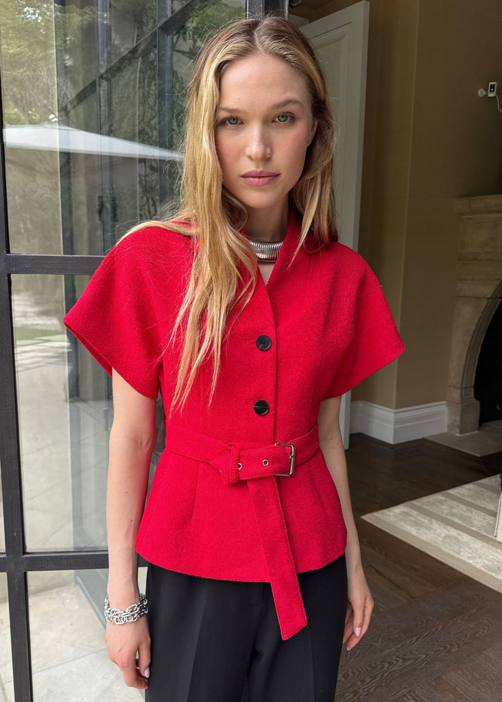 Woman wearing a red jacket with black buttons in an indoor setting