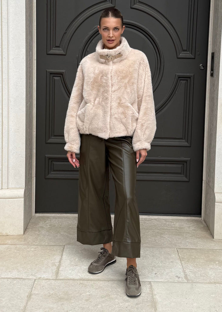 Person standing in front of a large black door with decorative patterns on a building facade.