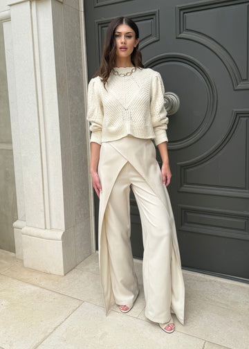Woman in a white outfit standing in front of a large door.