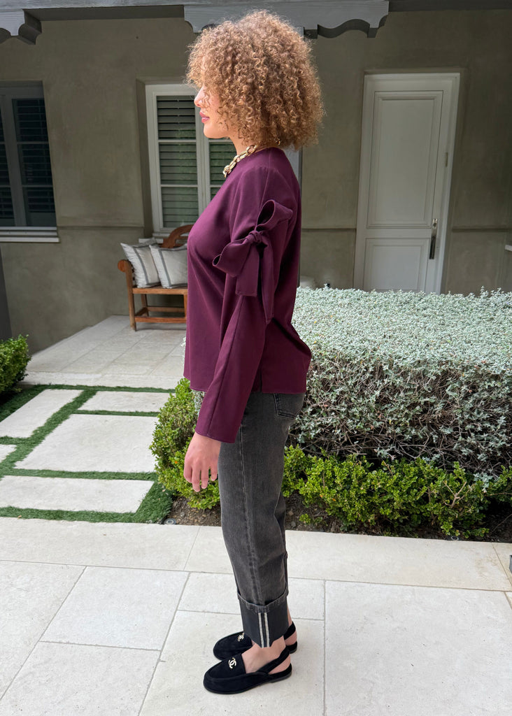 Woman standing on a patio in front of a house with greenery