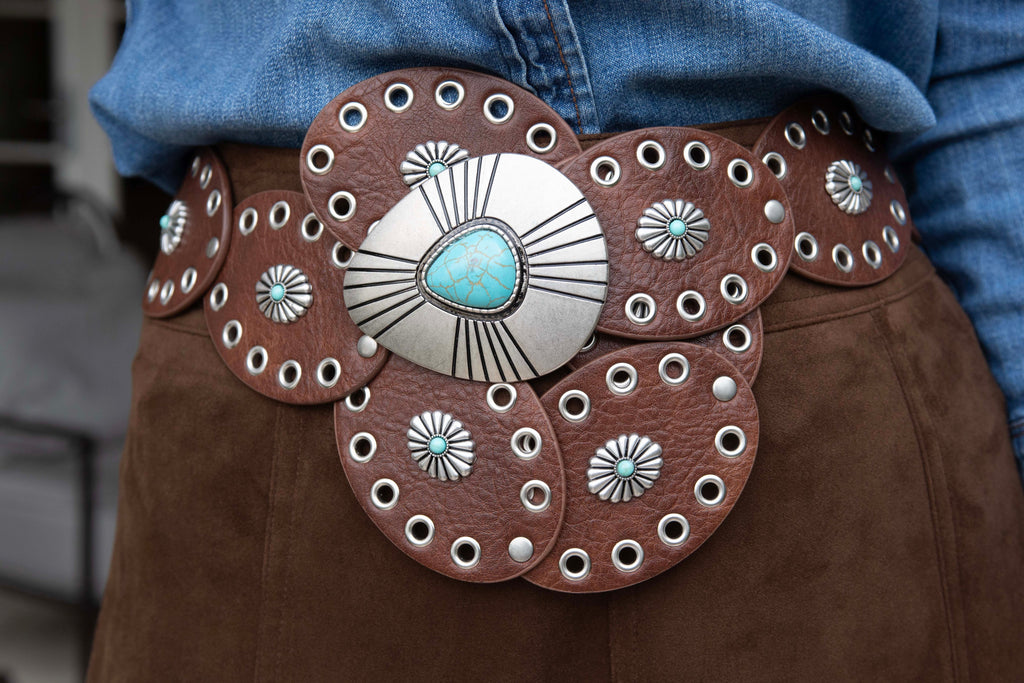 Close-up of a decorative belt with a large central buckle featuring turquoise stone and silver accents.