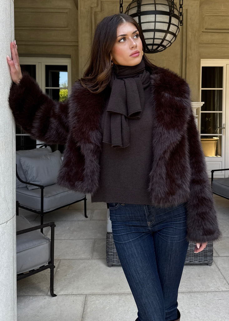 Woman wearing a fur coat in an outdoor setting with a building in the background