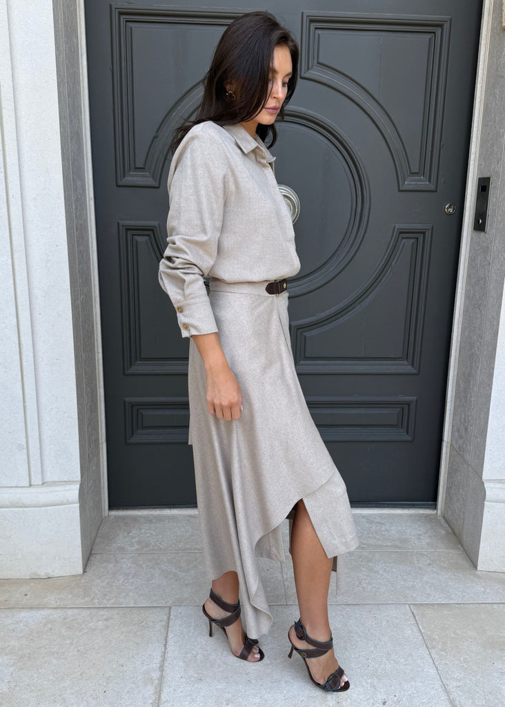 Woman in a beige outfit standing in front of a dark gray door.