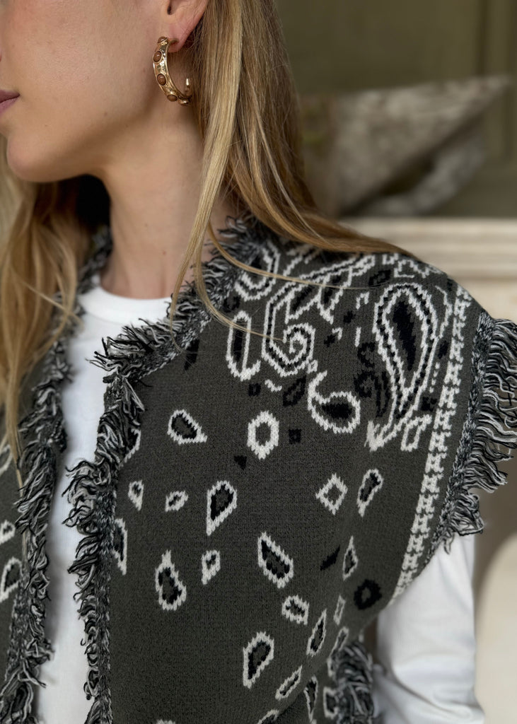 Close-up of a person wearing a black and white patterned scarf with fringe details.