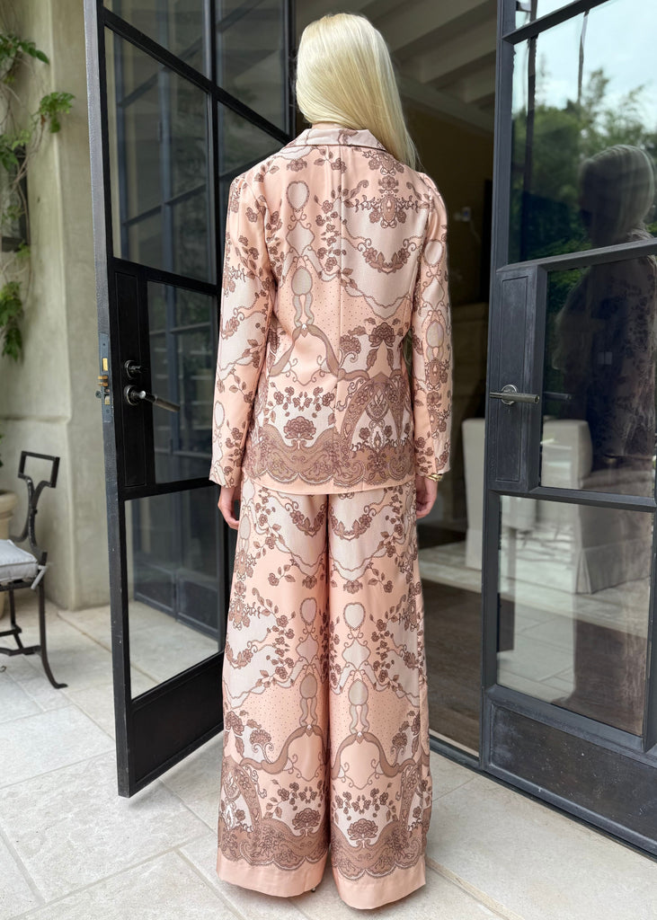 Woman in a pink floral outfit standing in front of glass doors.