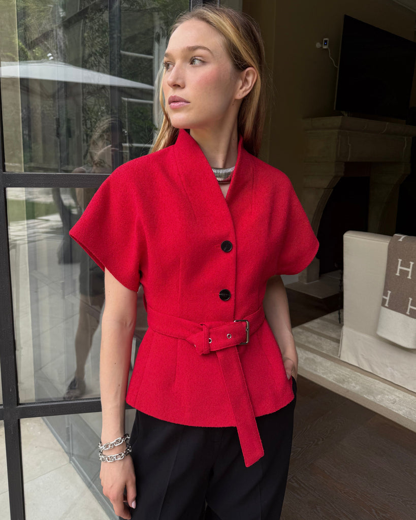 Woman wearing a red jacket with black buttons indoors.
