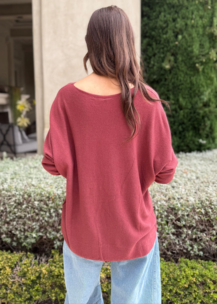 Person wearing a red sweater standing in a garden setting