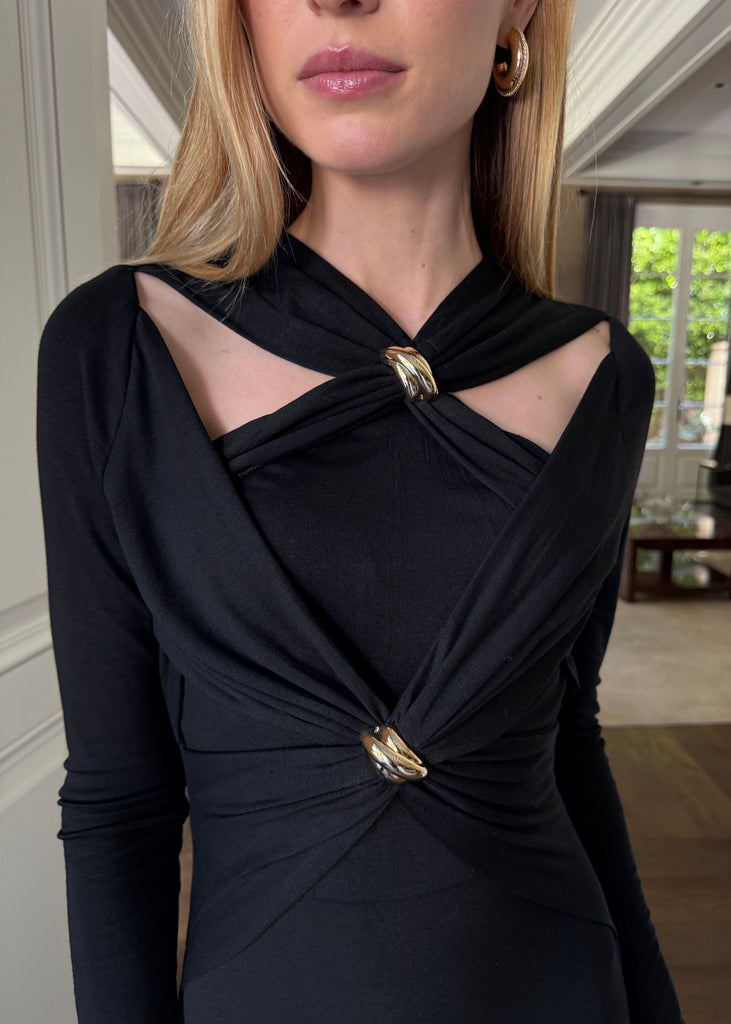 Woman wearing a black dress with gold accents in an indoor setting