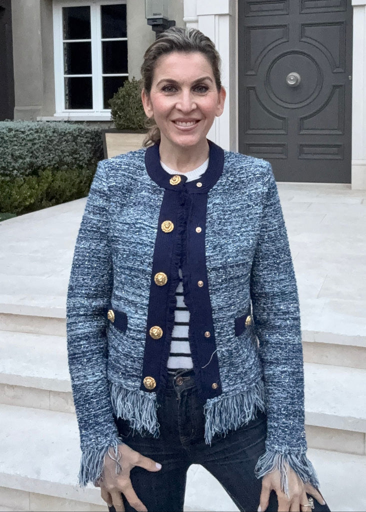 Woman standing in front of a large house with a gray door.