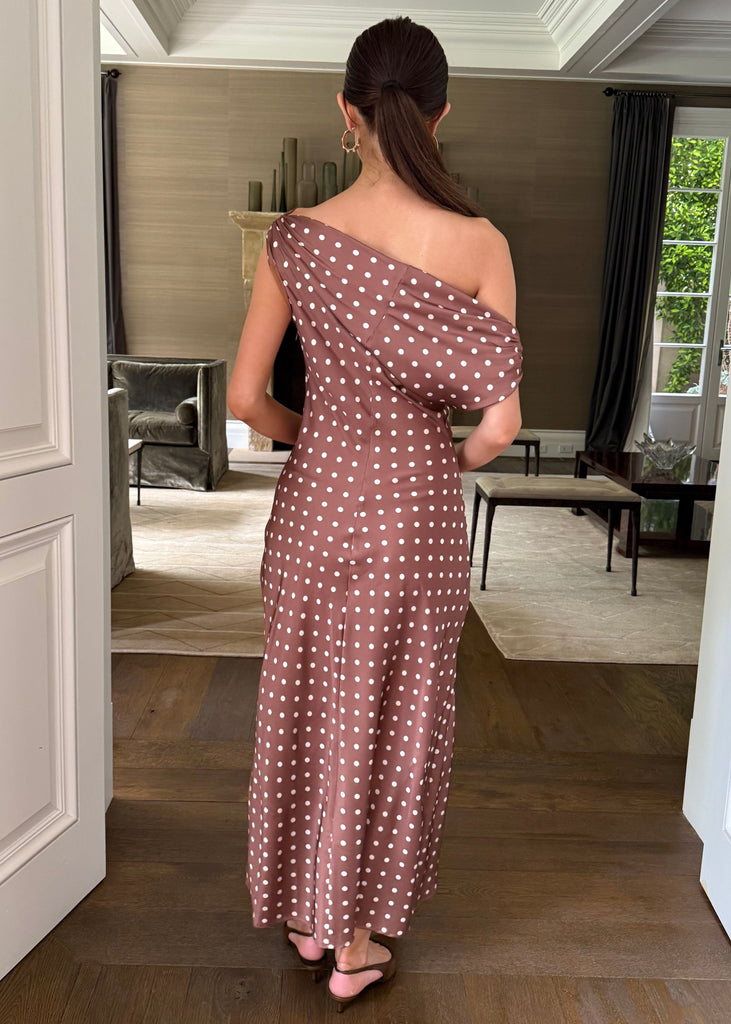 Woman in a polka dot dress standing in a doorway of a modern home.