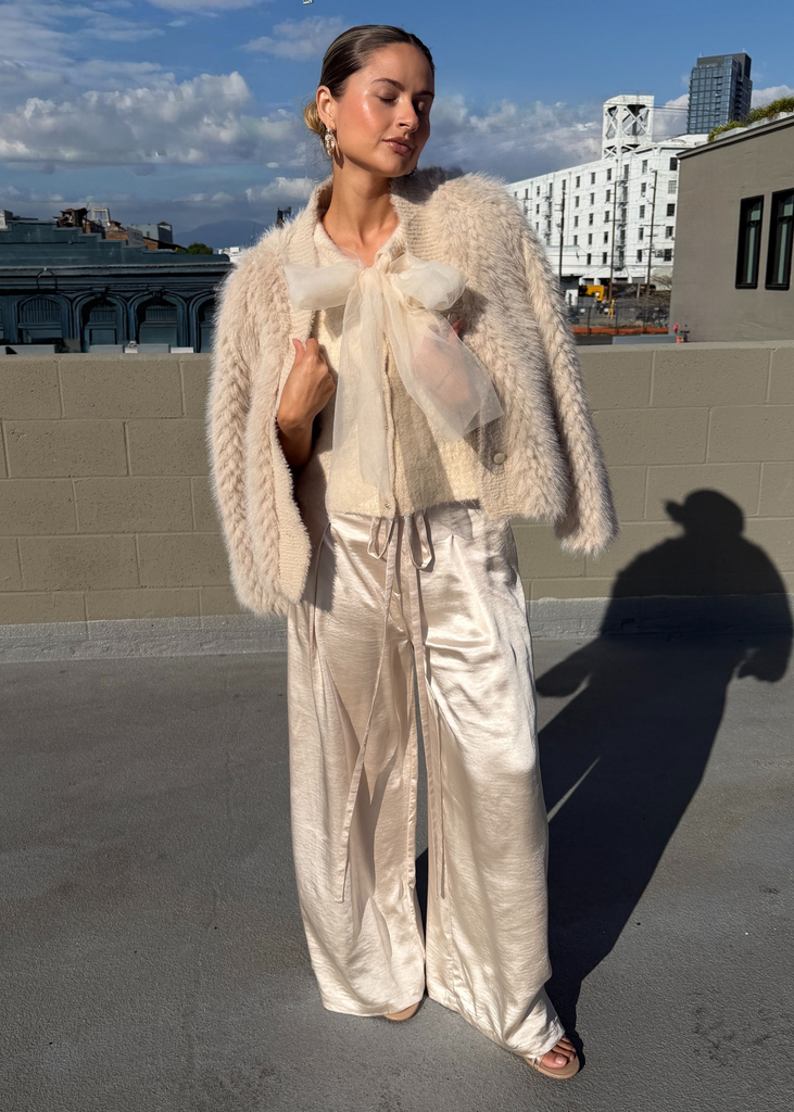 Person wearing a light-colored outfit on a rooftop with a cityscape background