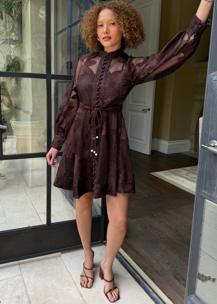 Woman in a brown dress standing in a doorway
