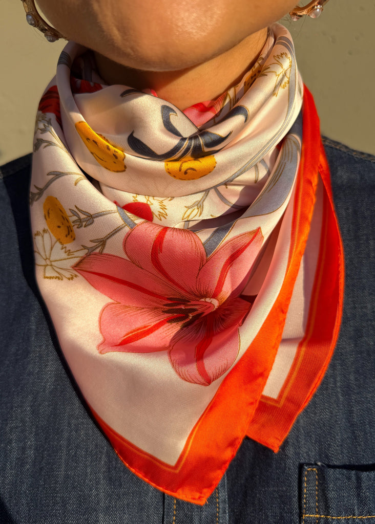 Person wearing a colorful floral scarf with a neutral background