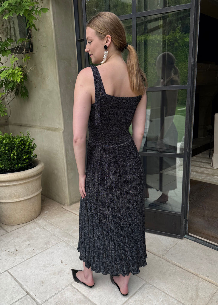 Woman in a black dress standing outside a building with a plant nearby