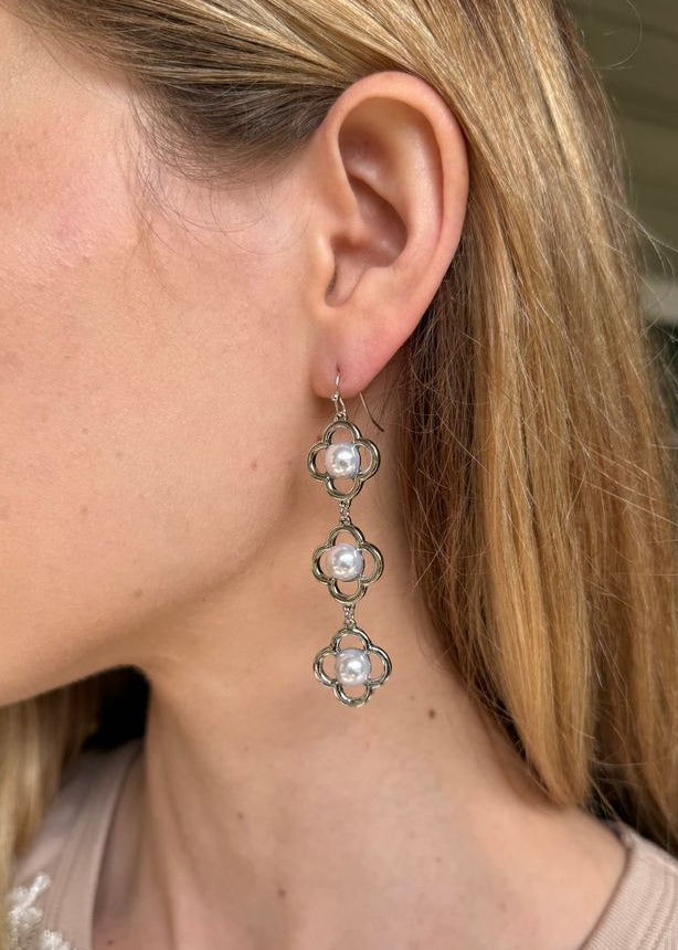 Close-up of a person wearing floral earrings with a neutral background